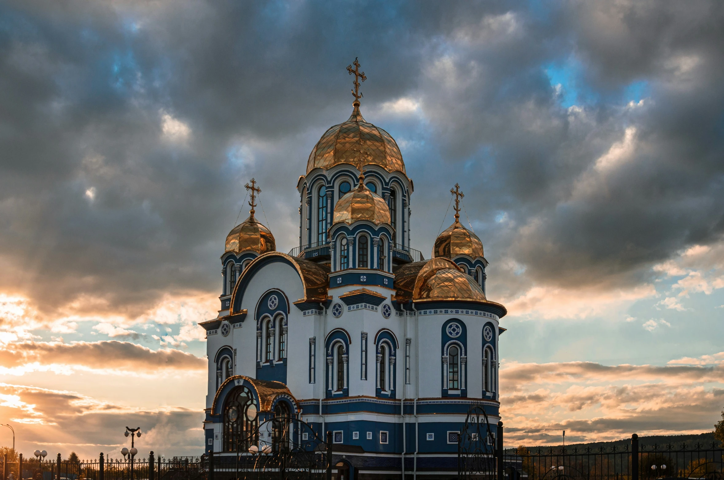 the sun is setting behind a large building with golden domes