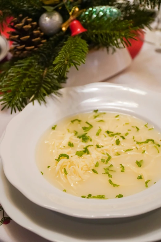 a bowl of soup in a white dish with a pine nch