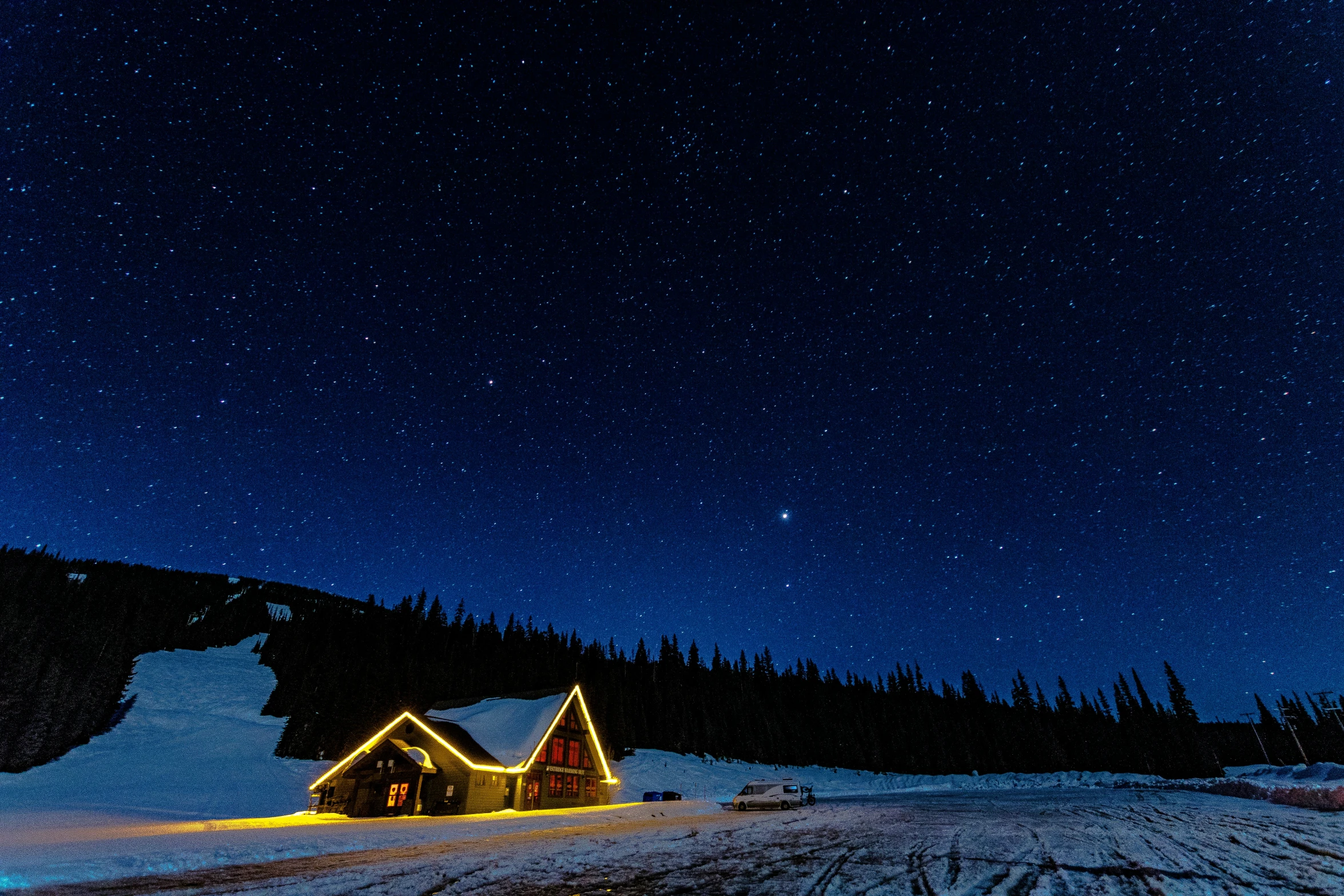 a house lit up in the snow at night