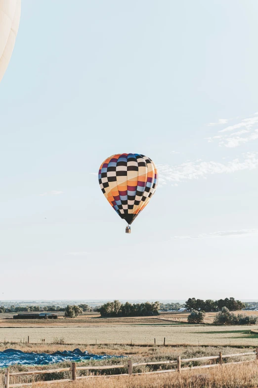 a multi colored  air balloon floats over the desert