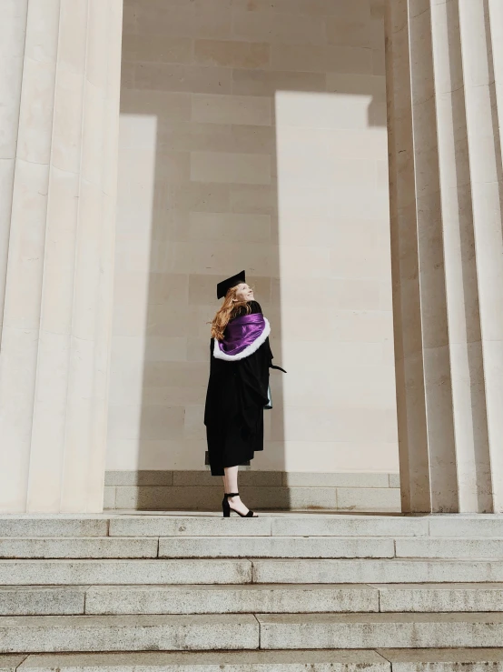 a woman wearing graduation attire is on stairs