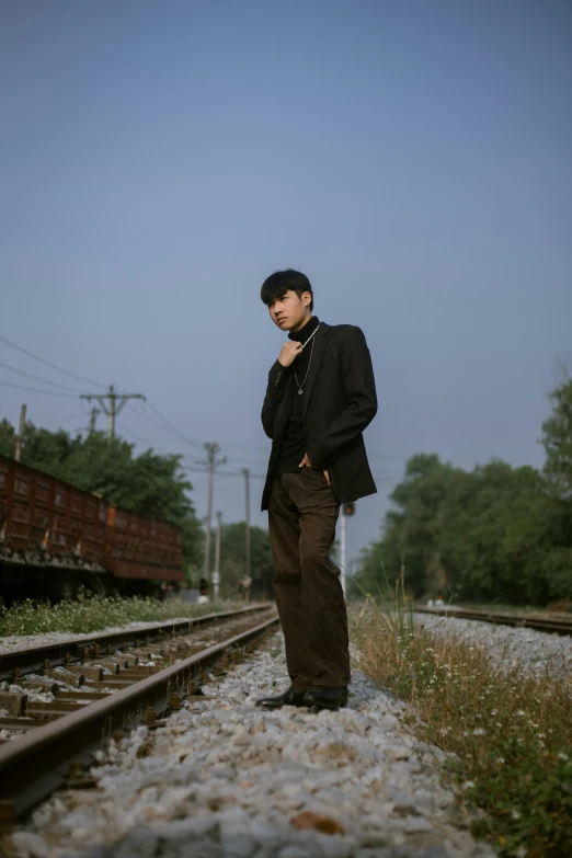 man standing in railroad tracks talking on his cell phone