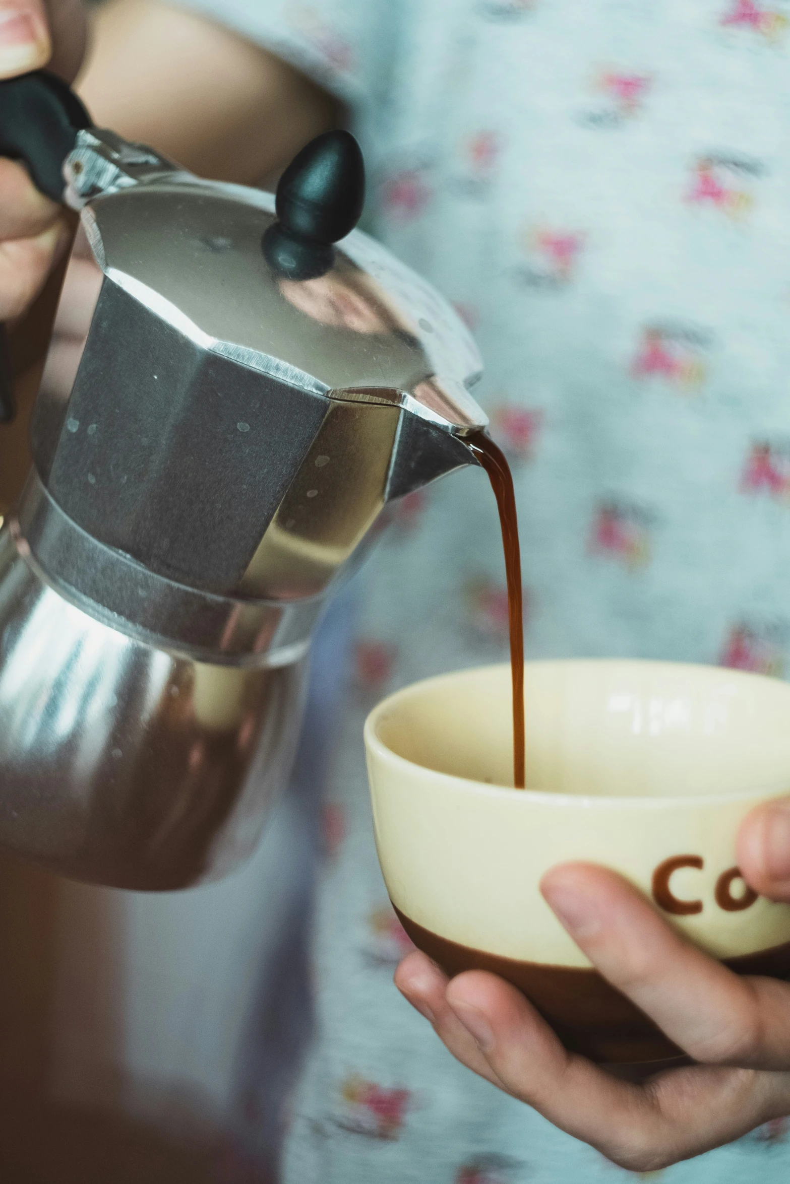 woman pouring coffee out of a coffee pot in her hands