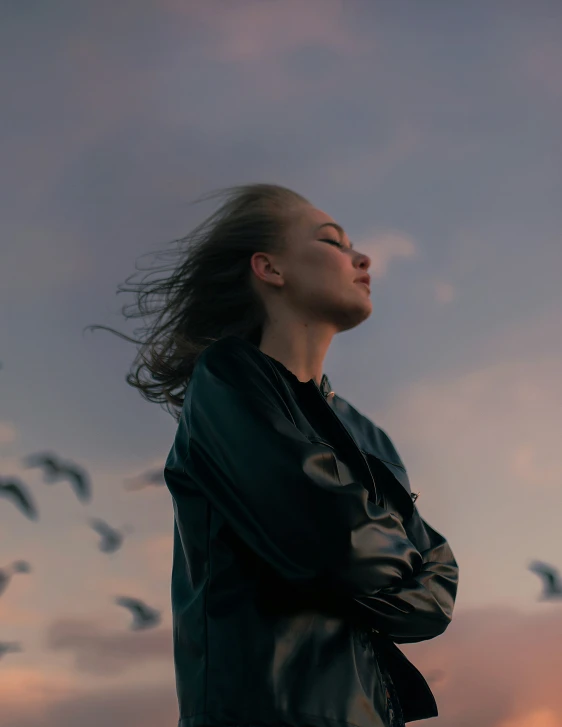 a woman with her eyes closed in the distance with birds flying