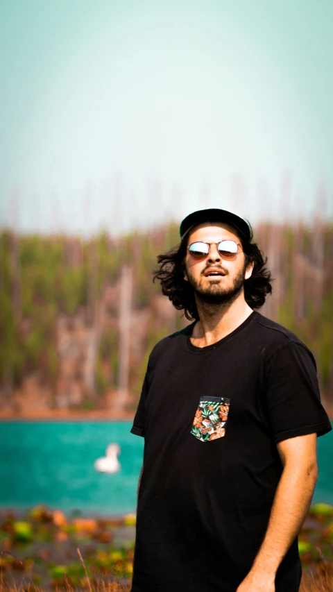 a man with a long dark hair standing in a grassy field