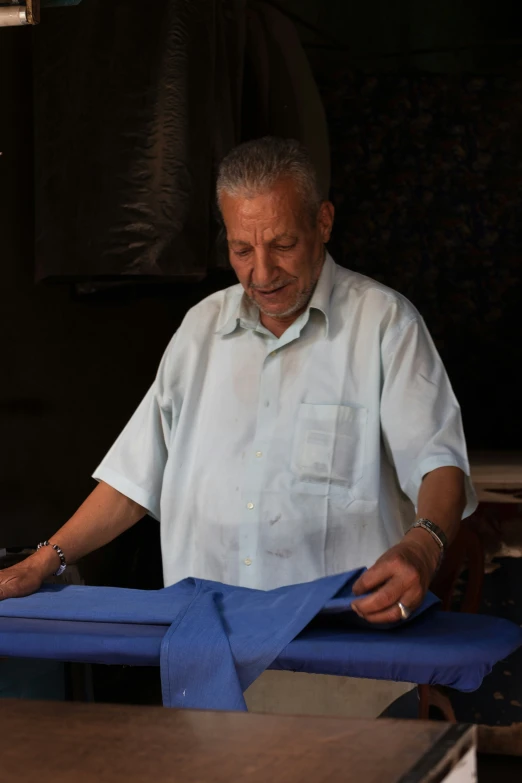 the old man is working on blue cloth