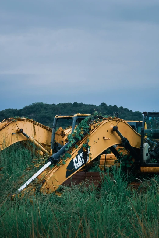 a bulldozer and tractor lie in grass