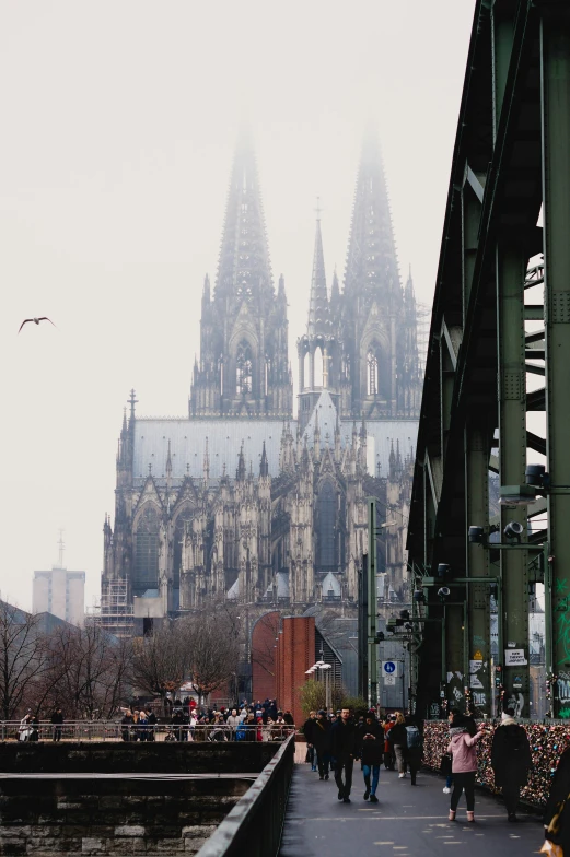 people walking on a bridge over looking a cathedral