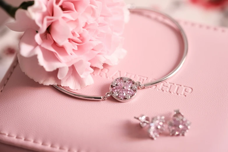 a pink flower on the ground next to a pink purse