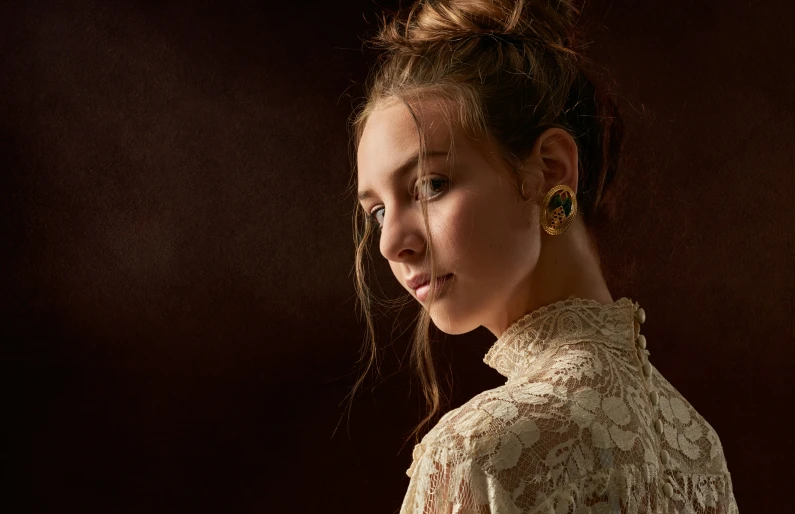 woman posing with black background in profile, wearing earrings