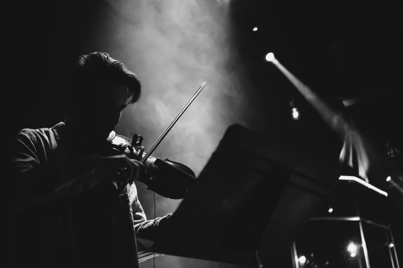 an adult playing the violin while lights shine in background