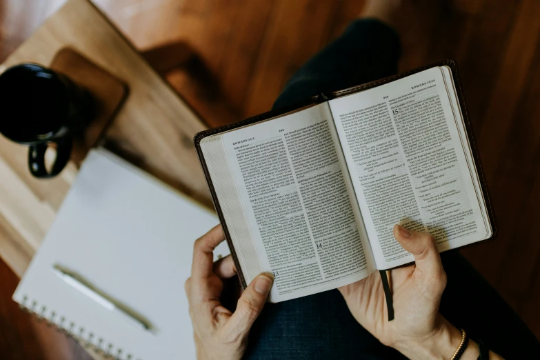 a person reading a book while holding a pen in their hand