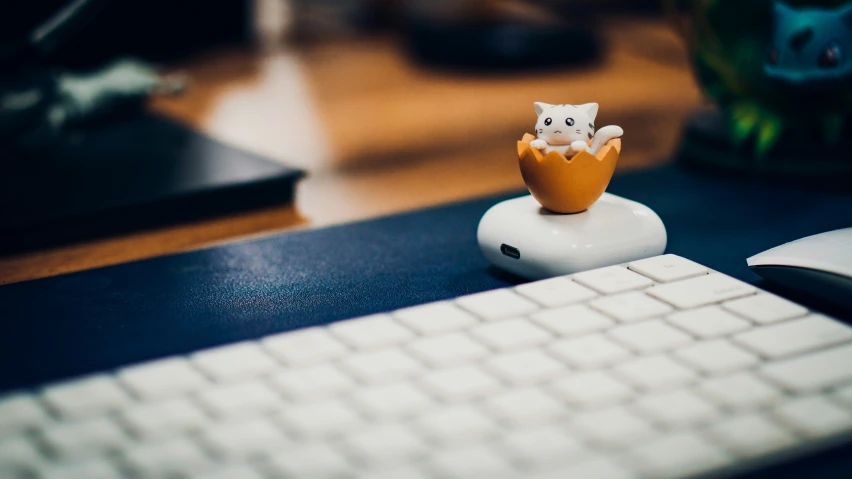 a toy owl sitting inside a egg near a keyboard