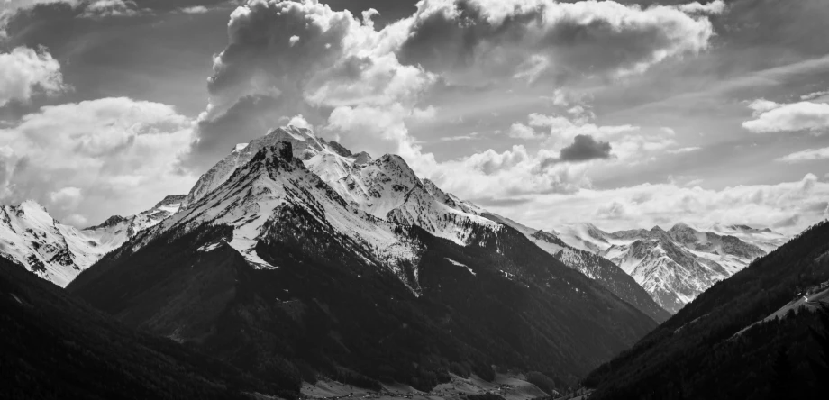 black and white pograph of a mountain peak with clouds above it
