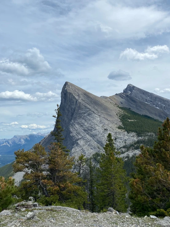 the view of a mountain, with rocks, trees, and hills in the foreground