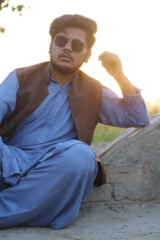 a man in a suit sits on the rocks near a tree