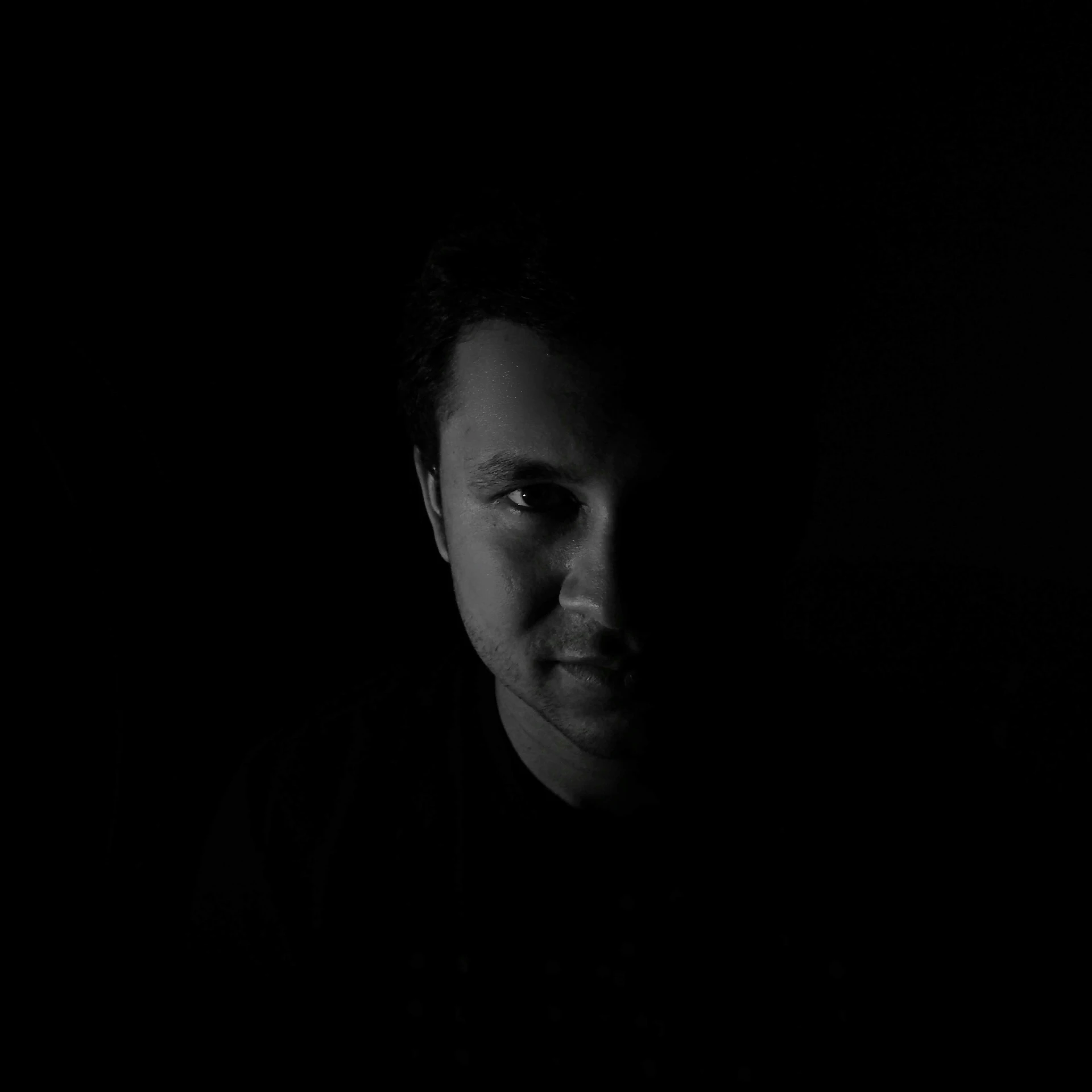 a young man with a black shirt in the dark