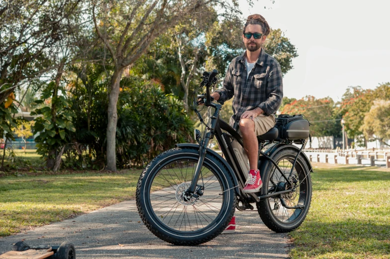 a young man is sitting on a bicycle near a bag and a tree