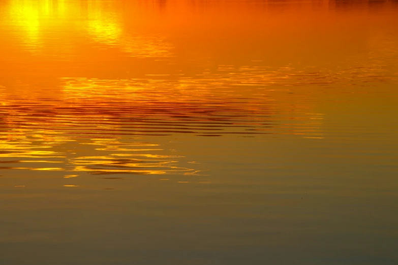 a colorful sunset reflects off the water of a lake