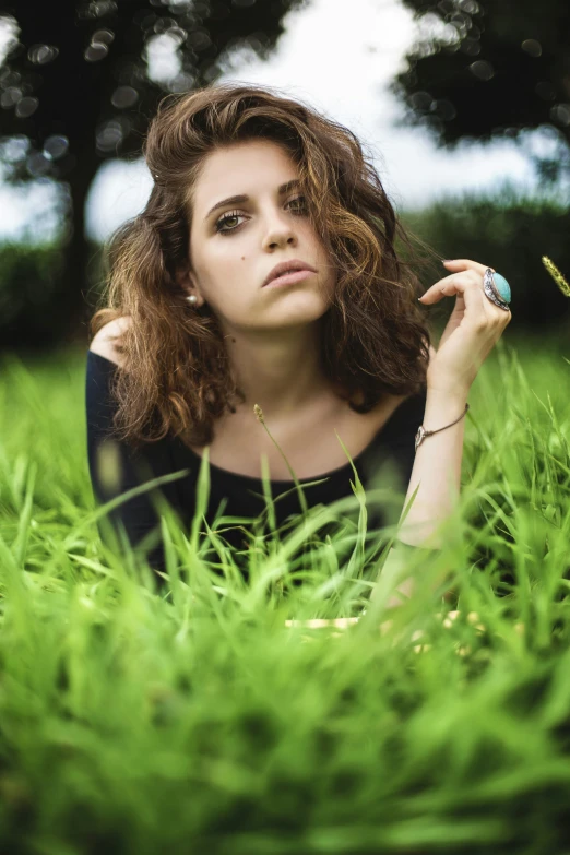 a woman laying in the grass with her hand on her head