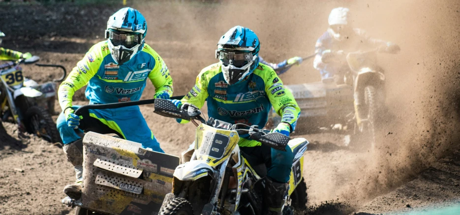 two dirt bikers racing on dirt bikes in the mud