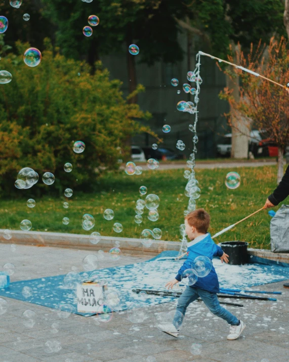 a little boy on some pavement playing with soap bubbles