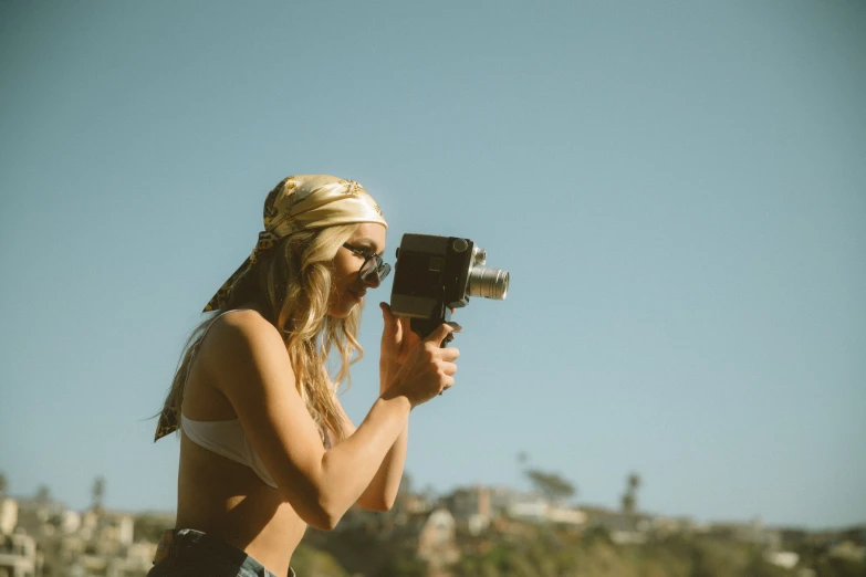 a woman is holding up her camera while she stands in the grass