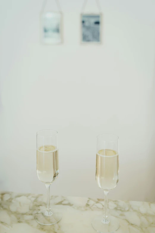 two wine glasses with liquid on marble table