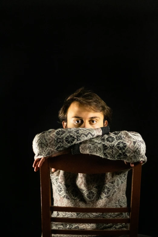 a young man is peeking into a chair