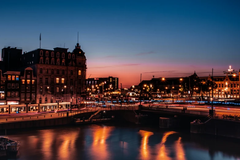 city lights lit up along a river at dusk