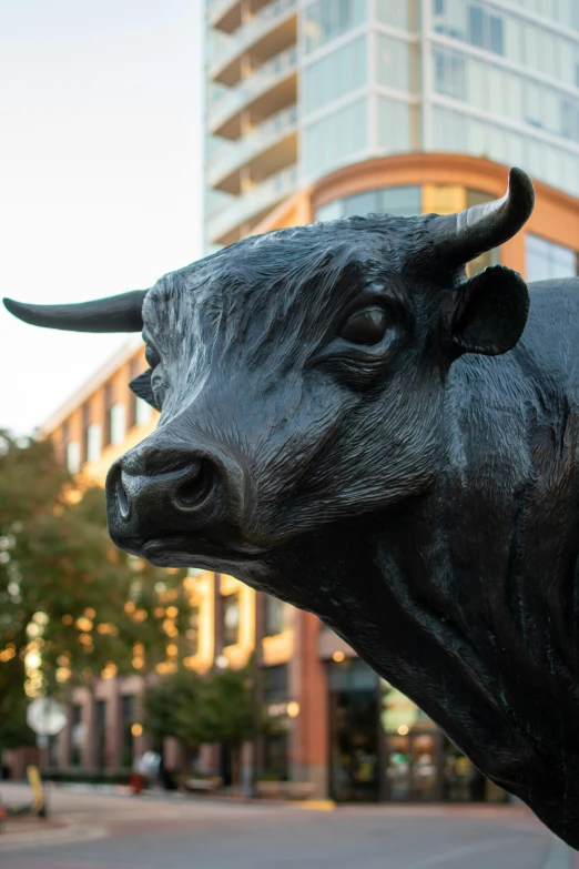 a bull statue in a city street with a tall building