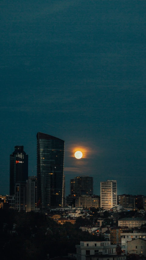 the city skyline at night with full moon