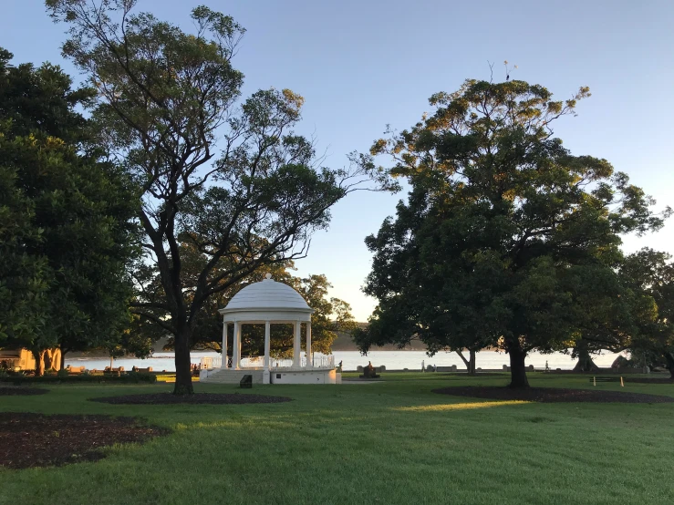 the white gazebo is next to a group of trees