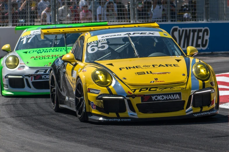 two porsche cars at the race, one being yellow
