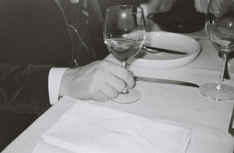 a man sitting in front of wine glasses at a table