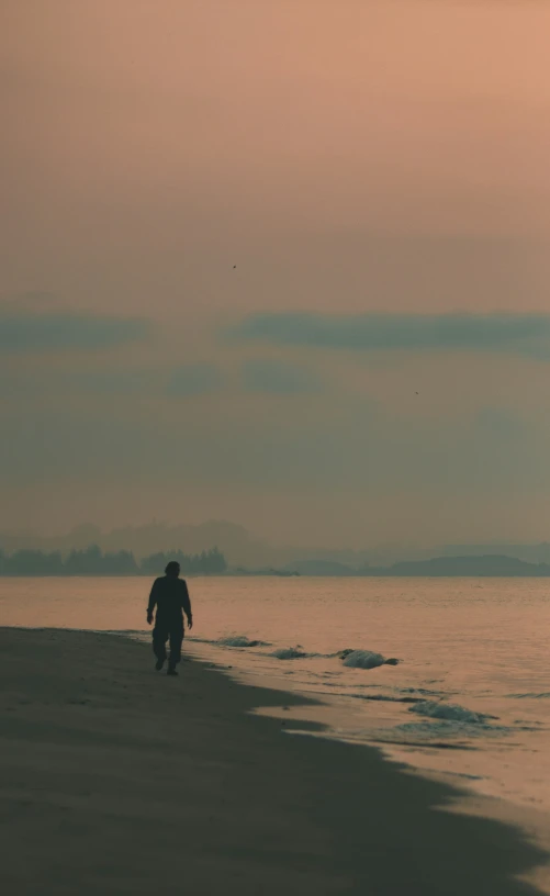 man walking on the beach during sunset