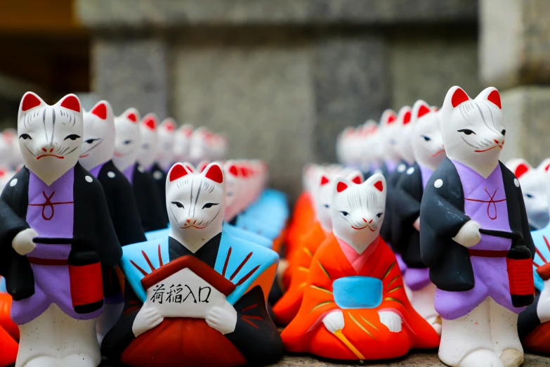 colorfully decorated clay figurines of cats holding an oriental plaque