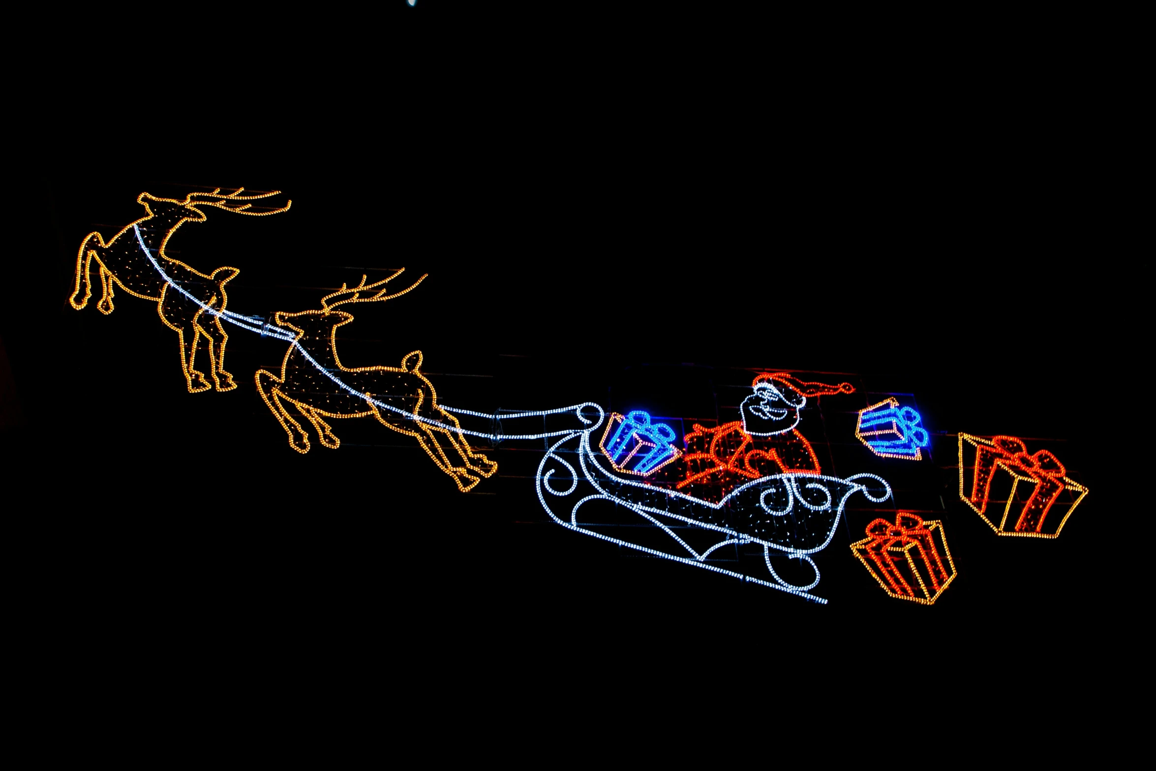 a lit up reindeer sleigh with gift bags on it