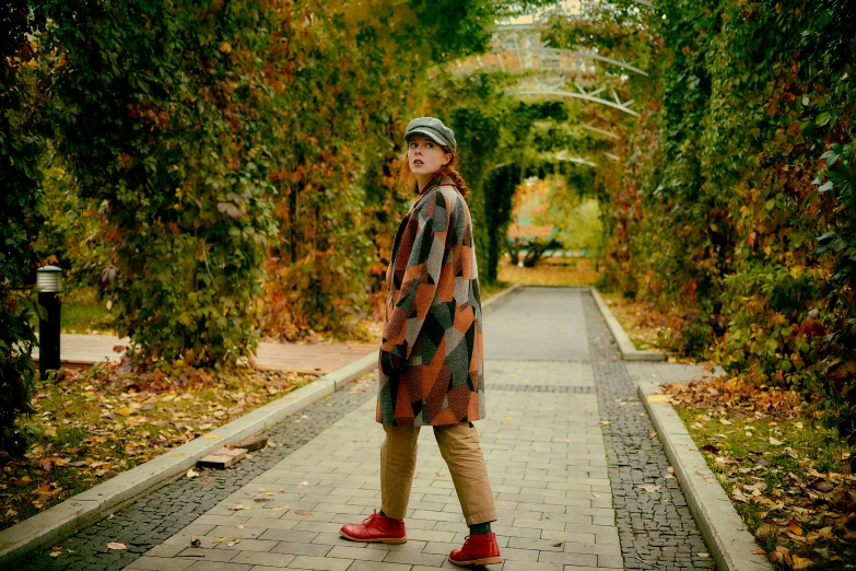 a woman is standing on the sidewalk under trees