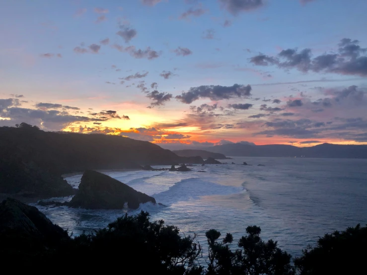 the sun is rising over some mountains, overlooking the water