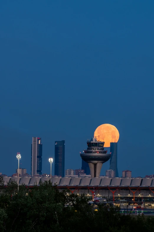 the moon sets over a city with buildings