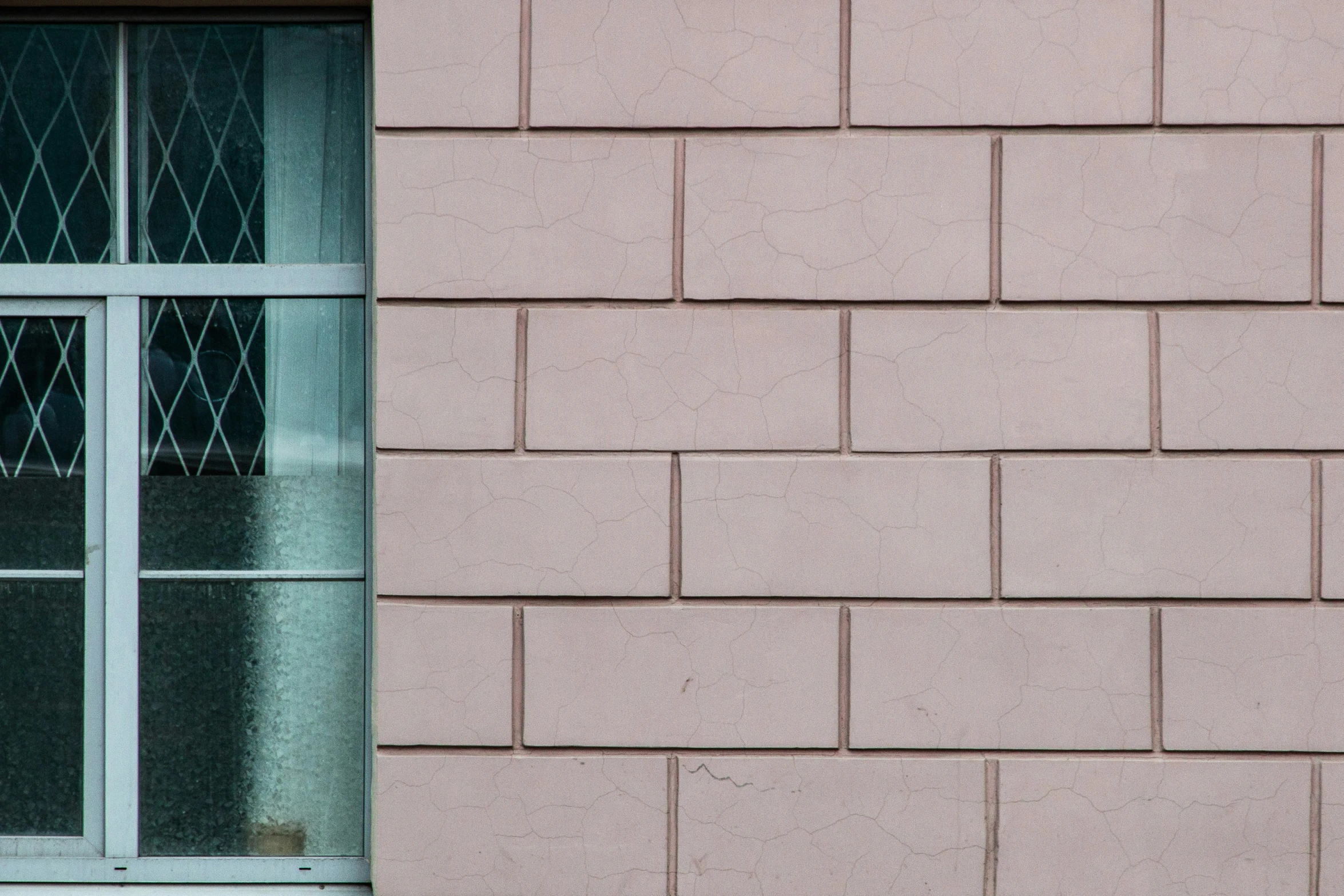 the corner of a brick wall with a large window