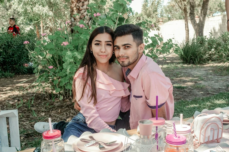 the couple is sitting at a picnic table outside