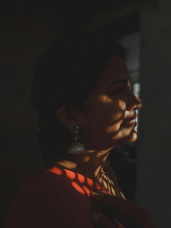 a woman is standing against the wall wearing earrings