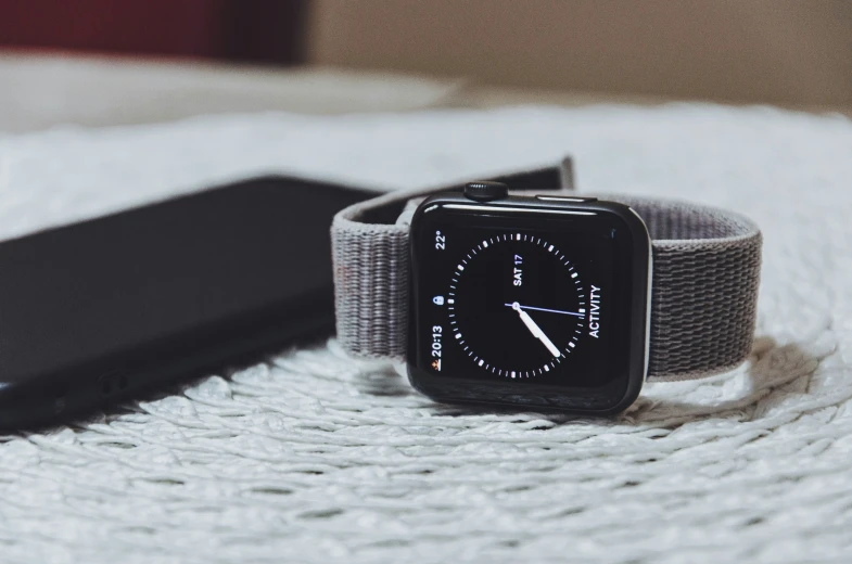 an apple watch sits on a bed next to a smart phone