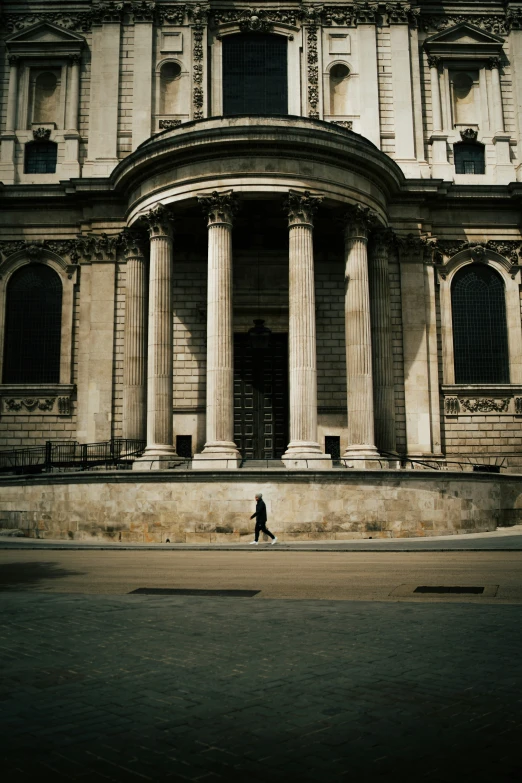 a person walking along the street in front of some columns