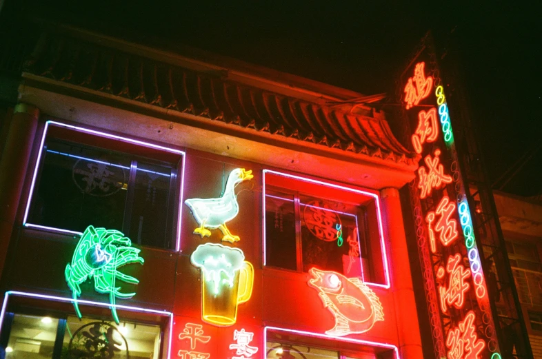 large neon signs adorn a building that is covered in chinese symbols