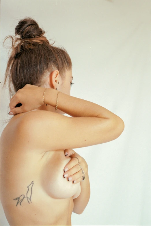 a woman with tattoos standing back to back with her hands on her chest