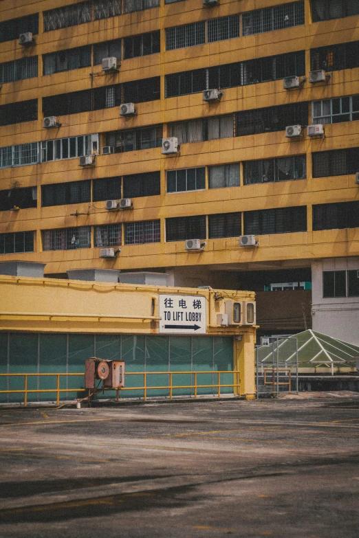 a yellow building with some windows next to a parking lot