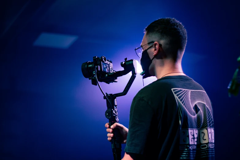 a man holding his camera in front of a blue background